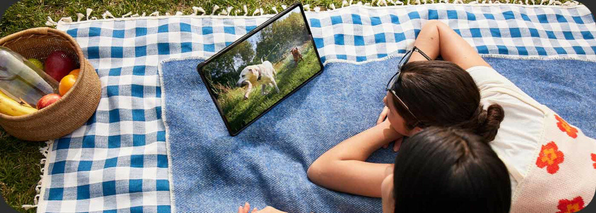 Tablet Samsung Galaxy Tab S9 grafika przedstawiająca dwie dziewczyny na kocu oglądające film na tablecie