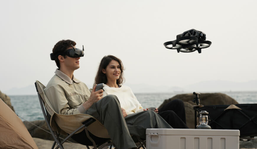 Dron DJI Avata Explorer Combo grafika przedstawia mężczyznę w goglach i kobietę patrzących na drona
