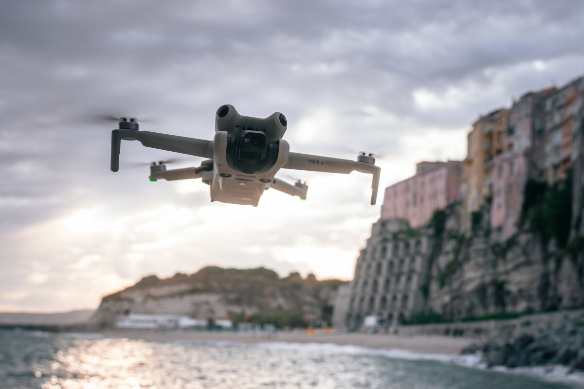 Dron DJI Mini 4 Pro Fly More Combo (DJI RC 2) grafika przedstawiająca dron latający nad plażą