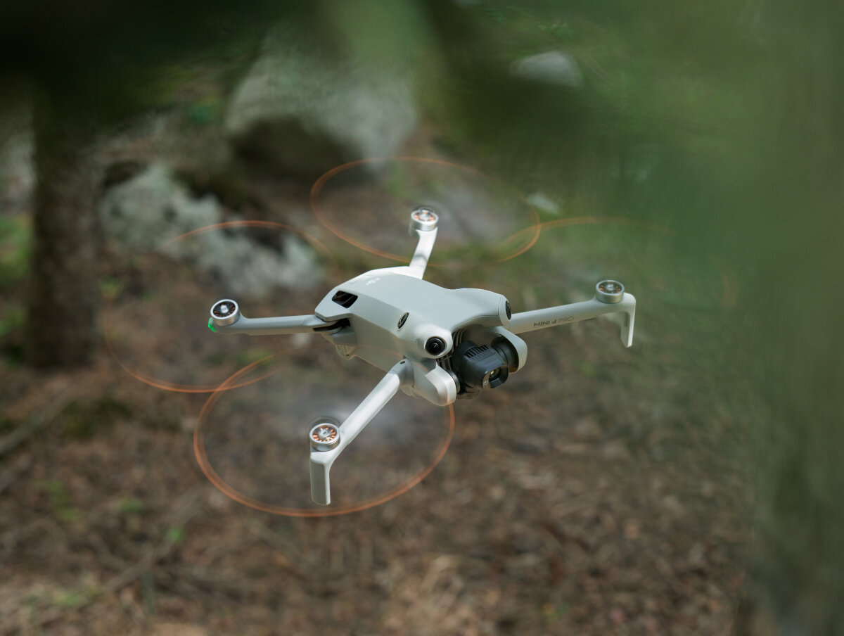 Dron DJI Mini 4 Pro (DJI RC 2) grafika przedstawiająca dron od góry unoszący się nad ziemią w lesie