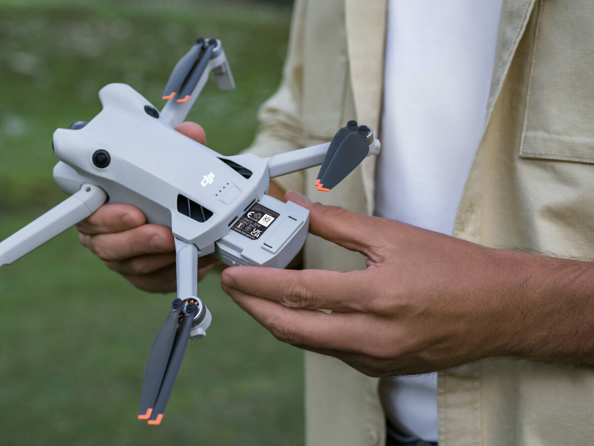 Dron DJI Mini 4 Pro (DJI RC 2) grafika przedstawiająca mężczyznę trzymającego dron w rękach